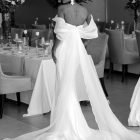 Back view of Anna wedding gown featuring dramatic flowing organza panels, off-the-shoulder sleeves and an elegant train.